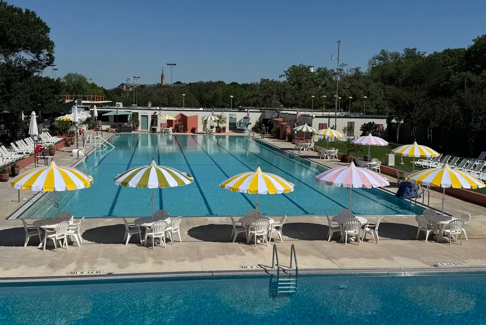 The same pool today, a row of yellow-and-white and pink-and-white striped umbrellas along the deck at dusk