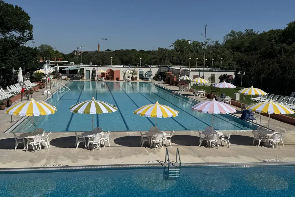 The Olympic pool on a clear morning, striped umbrellas and white chairs along the far deck